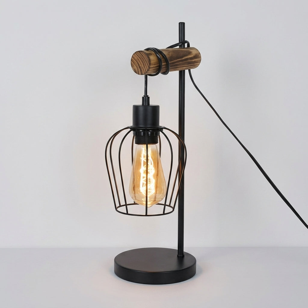 Industrial-style table lamp with a black metal wire cage shade, exposed Edison bulb, round black base, and a wooden accent on the arm, shown against a plain light background.
