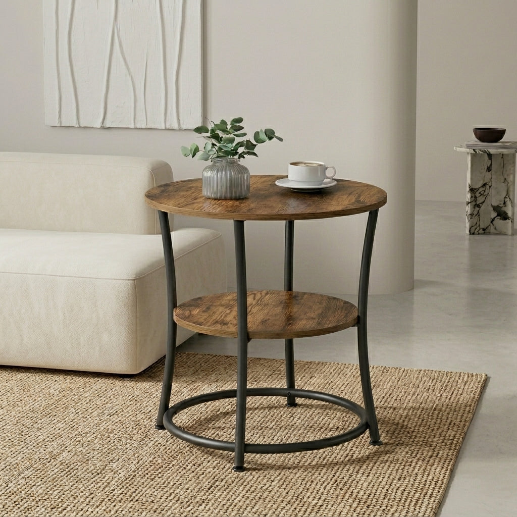 A round two-tier side table with a medium brown wood grain finish and black metal legs, styled in a living room setting next to a cream sofa.