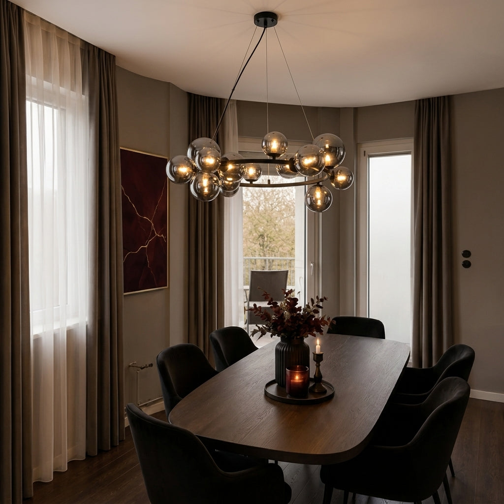 A modern multi-light chandelier with spherical glass shades hangs over a dark wood dining table and black chairs in a contemporary dining room with brown curtains and neutral walls.