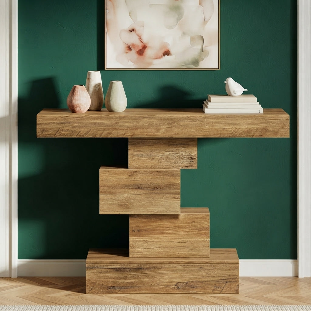 A rustic wood console table with a stacked, geometric block base, styled with vases, books, and a small bird figurine against a dark green wall.