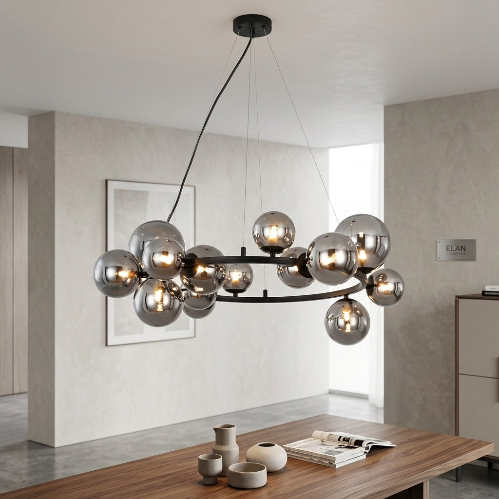 A modern chandelier with multiple reflective silver glass globes and warm exposed bulbs on a black circular frame, hanging in a contemporary dining room with a wooden table and neutral walls.