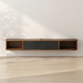 A modern floating wall-mounted media console with a dark wood finish and a central dark gray drawer, shown against a white wall with soft leaf shadows and light wood flooring.