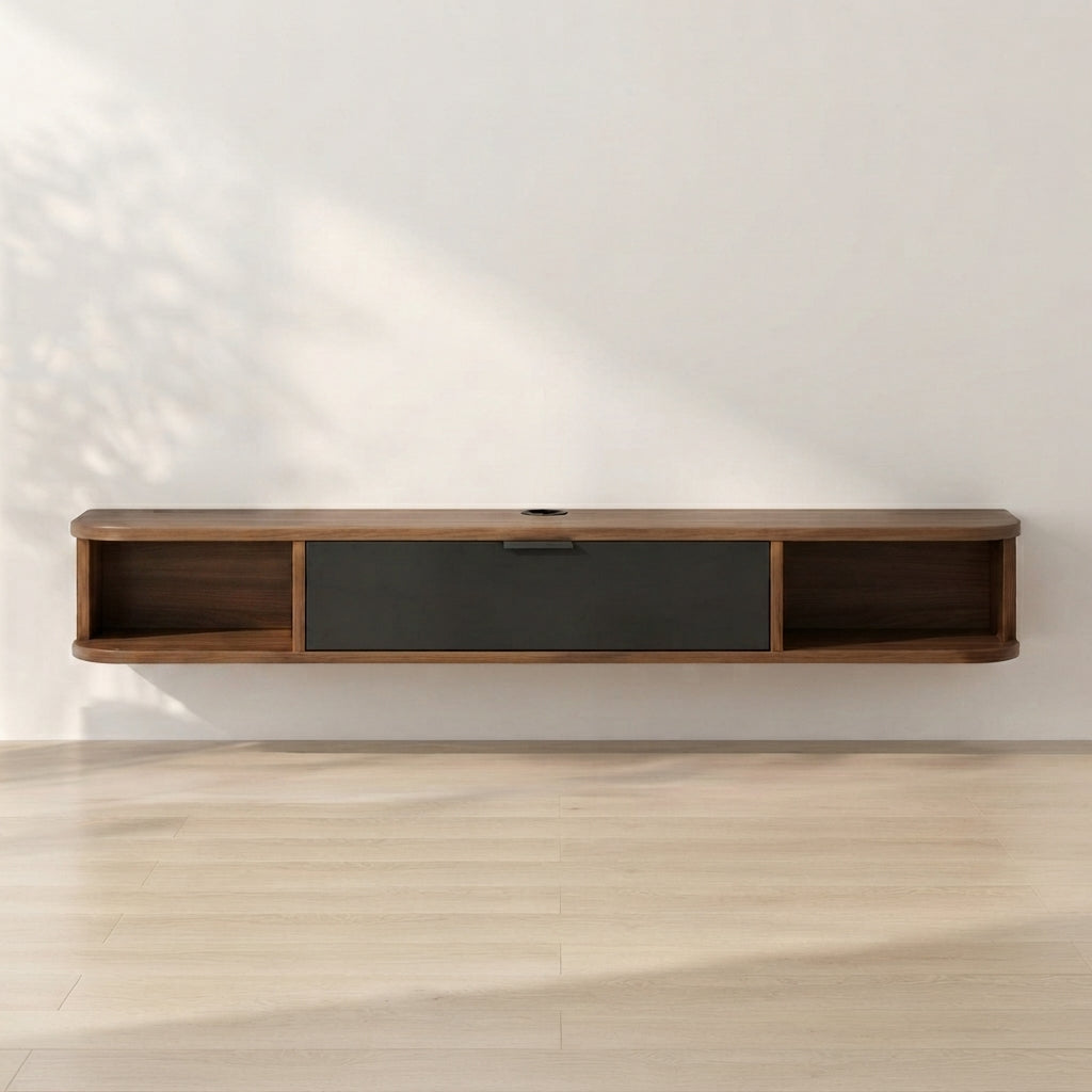 A modern floating wall-mounted media console with a dark wood finish and a central dark gray drawer, shown against a white wall with soft leaf shadows and light wood flooring.