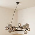 A modern multi-light chandelier with spherical smoked glass globes and a black metal frame, suspended from a ceiling in a minimalist room.