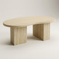 An oval stone coffee table made of light beige travertine, featuring a rounded top and two thick blocky legs, shown on a neutral light gray background.