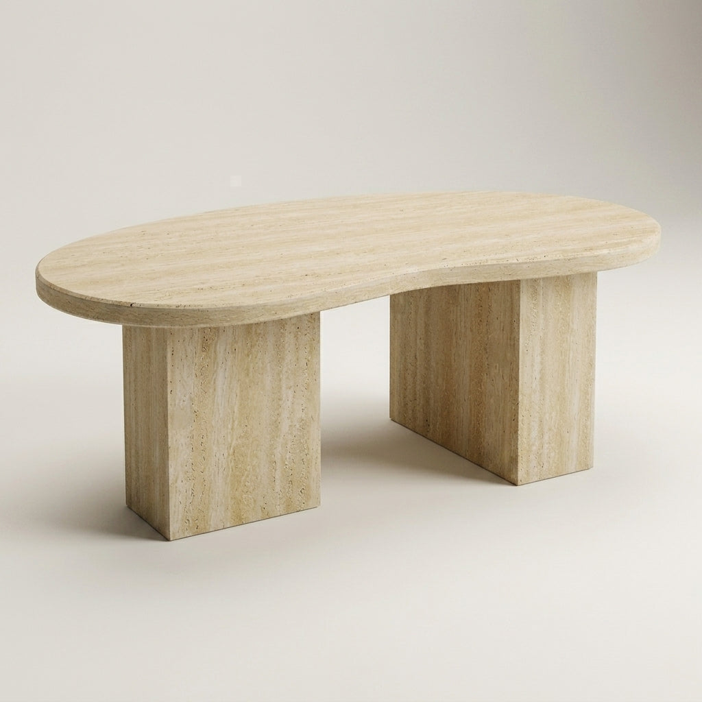 An oval stone coffee table made of light beige travertine, featuring a rounded top and two thick blocky legs, shown on a neutral light gray background.