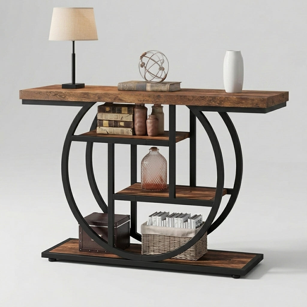 A rustic console table with a dark brown wood top and shelves, supported by a black metal circular frame structure, styled with a lamp, books, vases, and baskets against a light gray background.