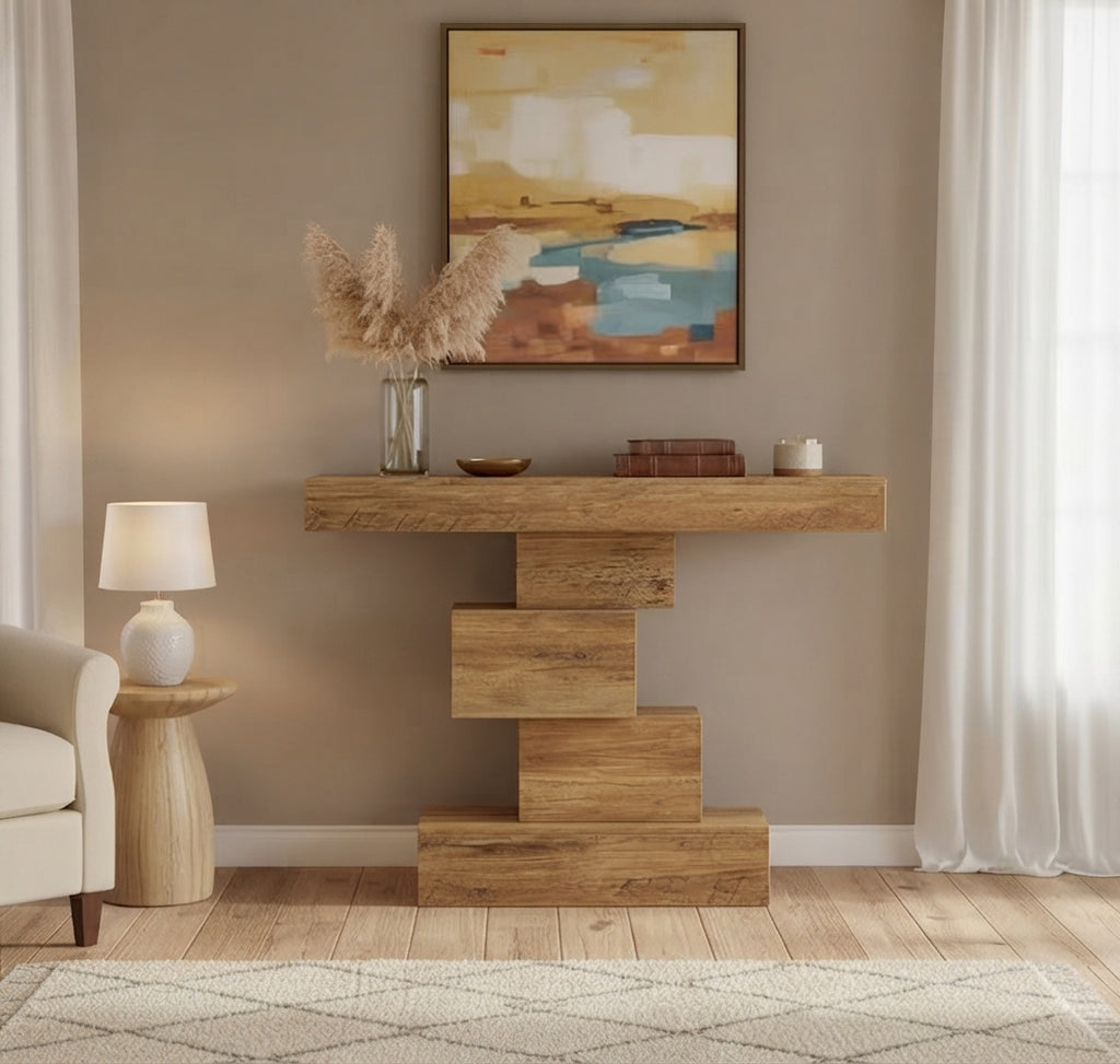 A rustic wooden console table with a stacked block base, styled in a living room setting with a lamp, side table, abstract wall art, and sheer curtains.