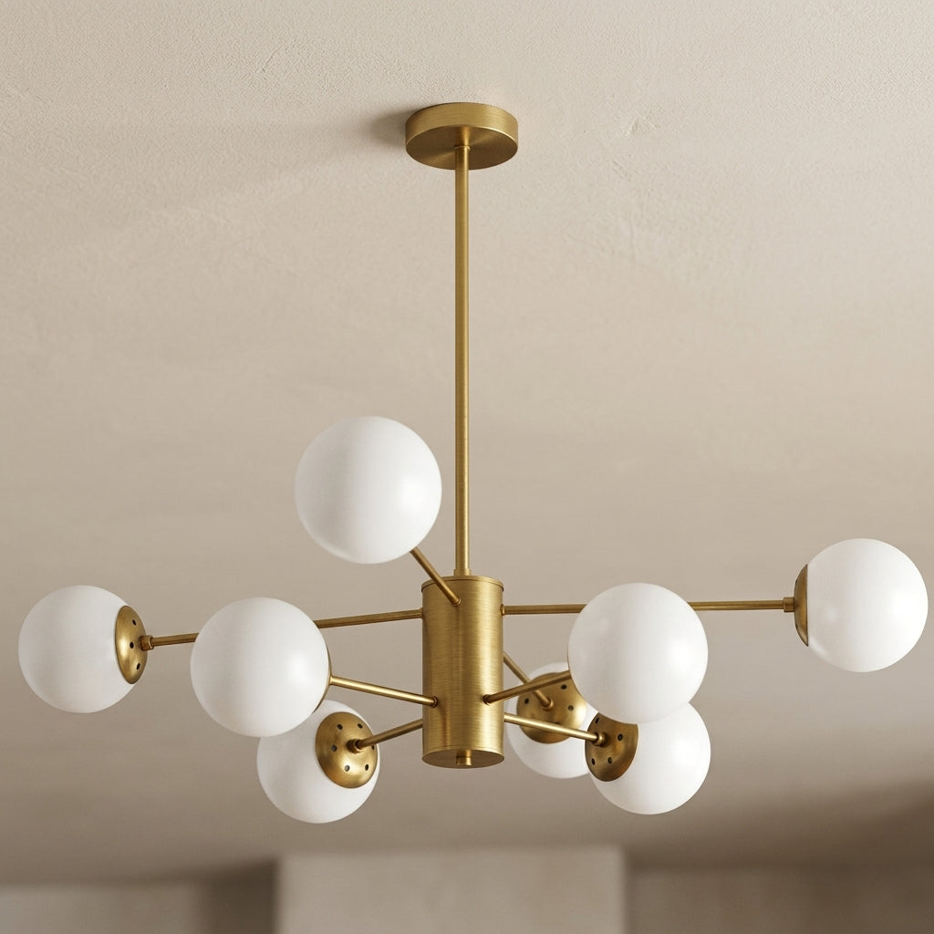A modern six-light sputter-style ceiling light fixture with a brushed brass/gold metal frame and white spherical glass shades, shown hanging from a ceiling in an indoor room setting.