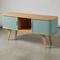 A mid-century modern sideboard cabinet with a light natural wood top and legs, and ribbed turquoise blue doors, shown on a concrete floor against a neutral gray wall.