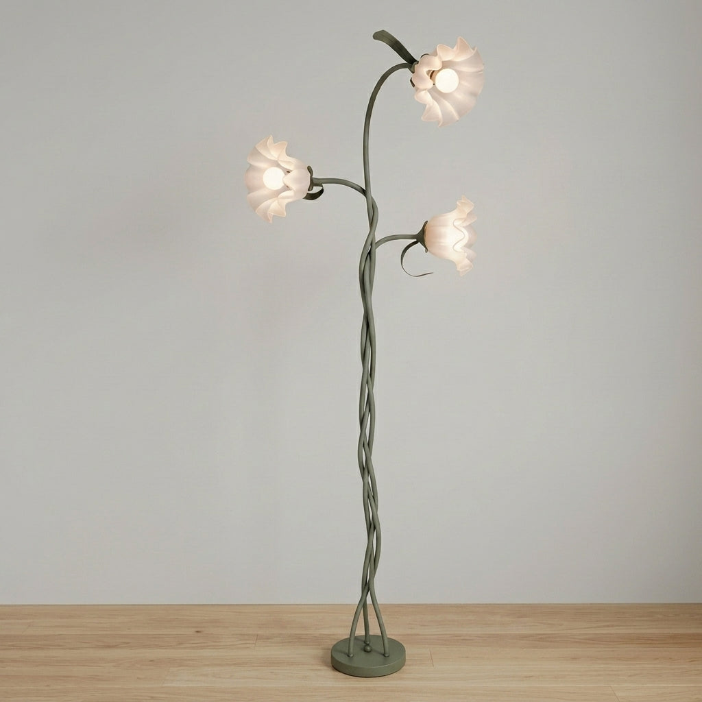 A unique three-light floor lamp designed like a twisted tree trunk with three flower-shaped shades, shown on a light wood floor against a neutral gray wall.
