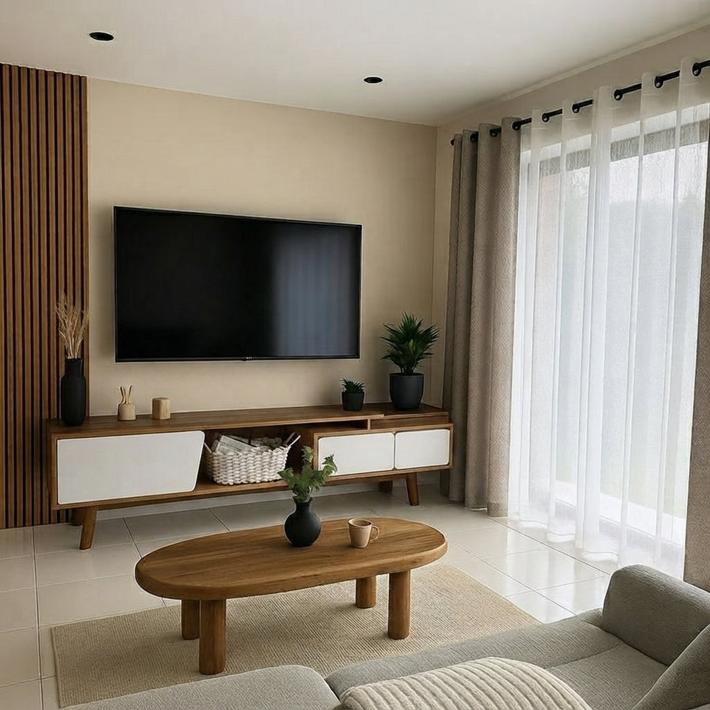 A modern living room featuring a mid-century style wooden TV stand with white drawer fronts, a wall-mounted black TV, a round wooden coffee table, and a light gray sofa in front of sheer white curtains.